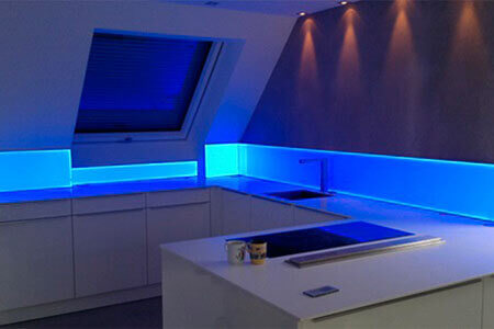 Een keukentje met spatbescherming van acrylglas met blauwe achtergrondverlichting